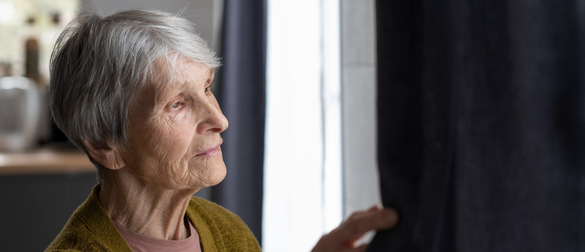 Old woman looking out of a window | Caring for a loved one with Alzheimers | Petros | Resilience